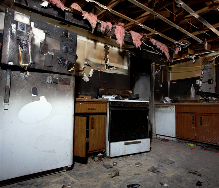 a fire damaged kitchen with soot covering the walls and ceiling